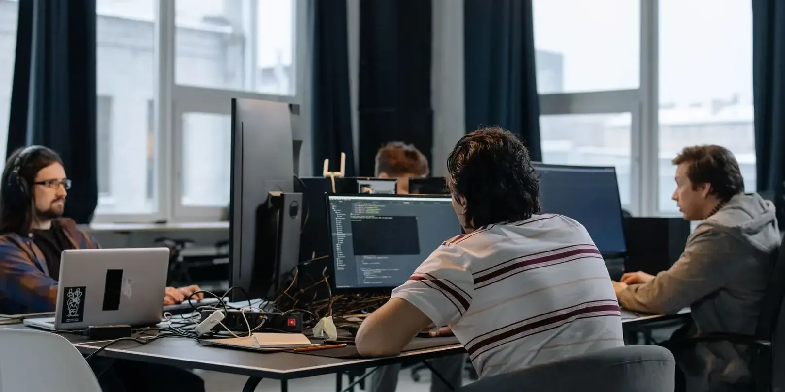 Software engineers working together at a shared desk with multiple monitors in a modern office